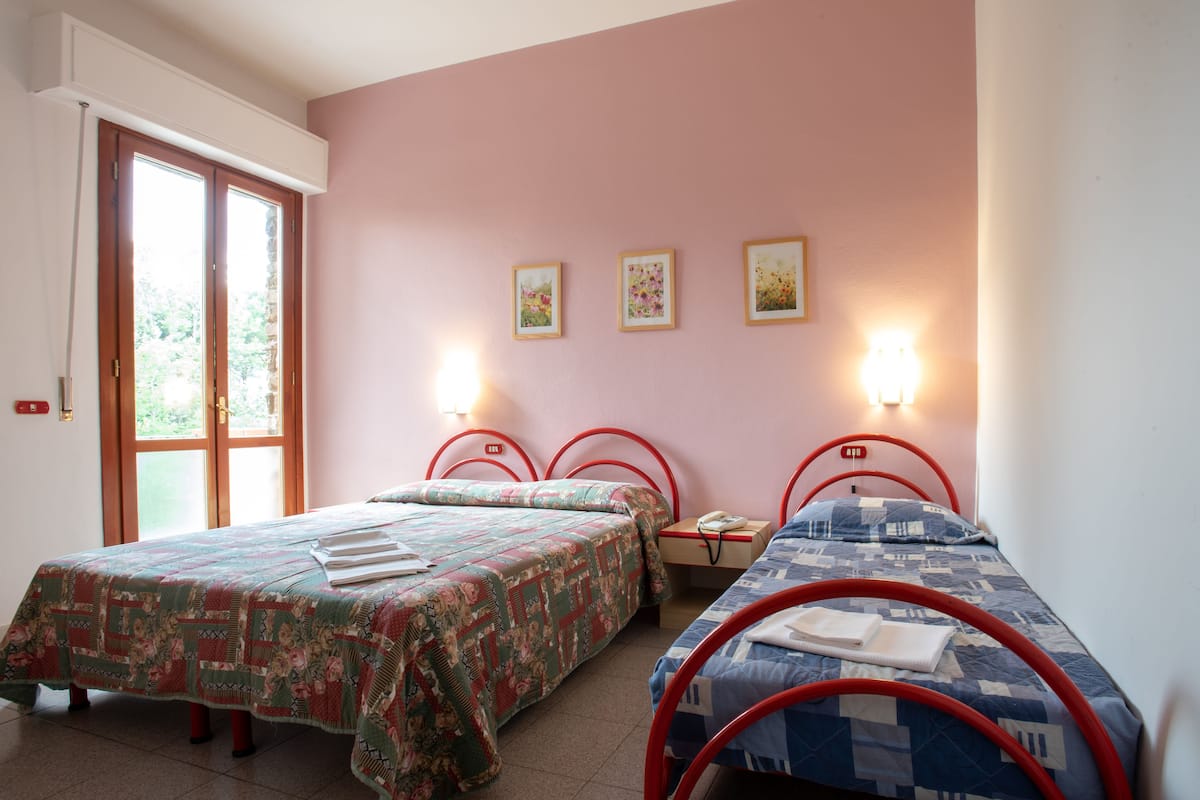 A room with two beds, a window, and three wall-mounted lights.