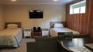 A room with two beds, a TV, a small table, and a chair.
