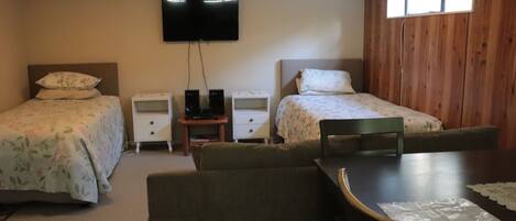 A room with two beds, a TV, a small table, and a chair.