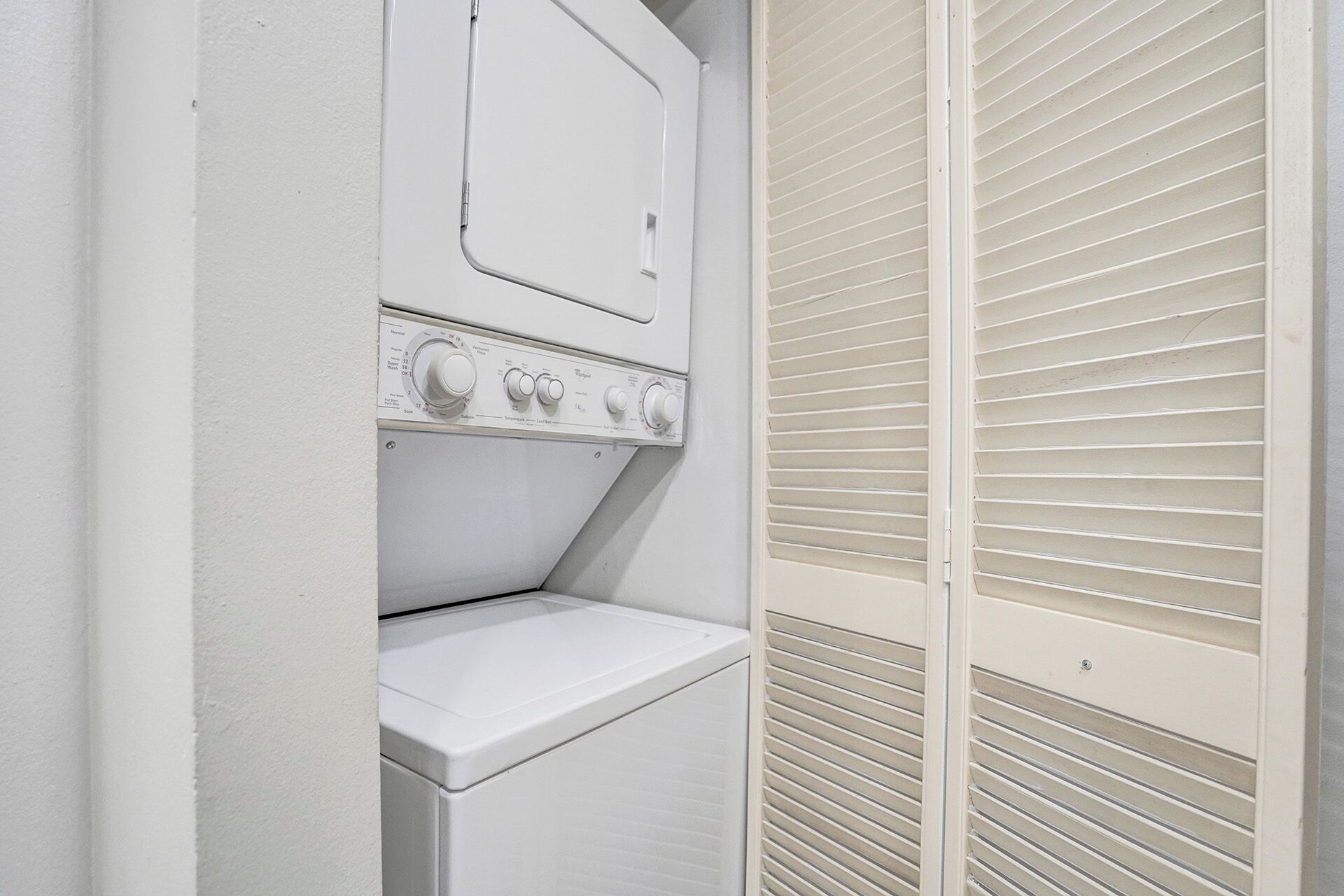 A compact laundry area with a washing machine, a dryer, and a built-in shelf.