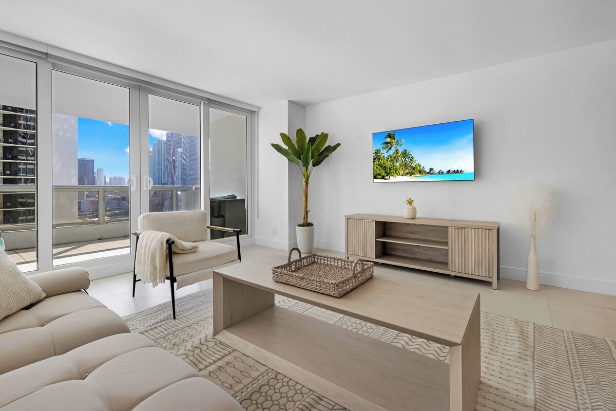 Una sala de estar moderna con un sofá, una mesa de centro y un televisor montado en la pared.