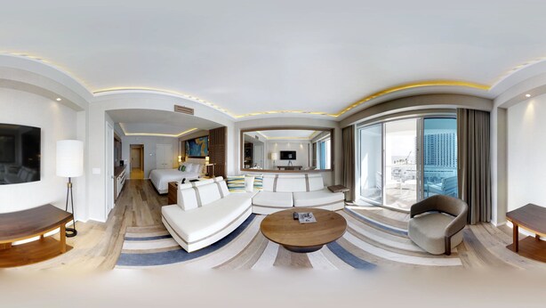 Une chambre d’hôtel moderne au design épuré, dotée d’un grand lit, d’un canapé, d’une table basse et d’un téléviseur.