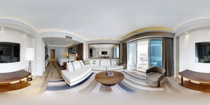 A modern hotel room with a curved layout, a large bed, a sofa, a coffee table, and a TV. - Beachfront Condo in Central Beach (Fort Lauderdale)