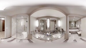 Une salle de bain spacieuse avec un meuble-lavabo aux lignes courbes, un grand miroir et une douche à parois de verre.