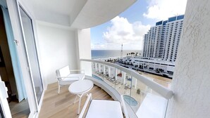 Un balcon avec vue sur la plage et un immeuble de grande hauteur.
