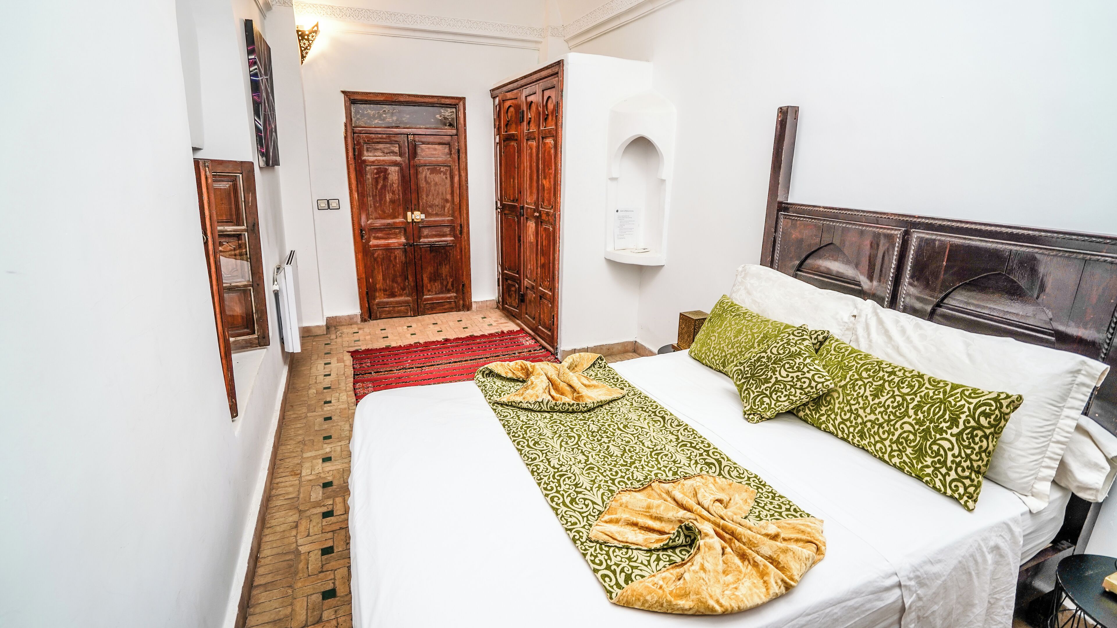 Un dormitorio con una cama, almohadas, una alfombra y un armario de madera.