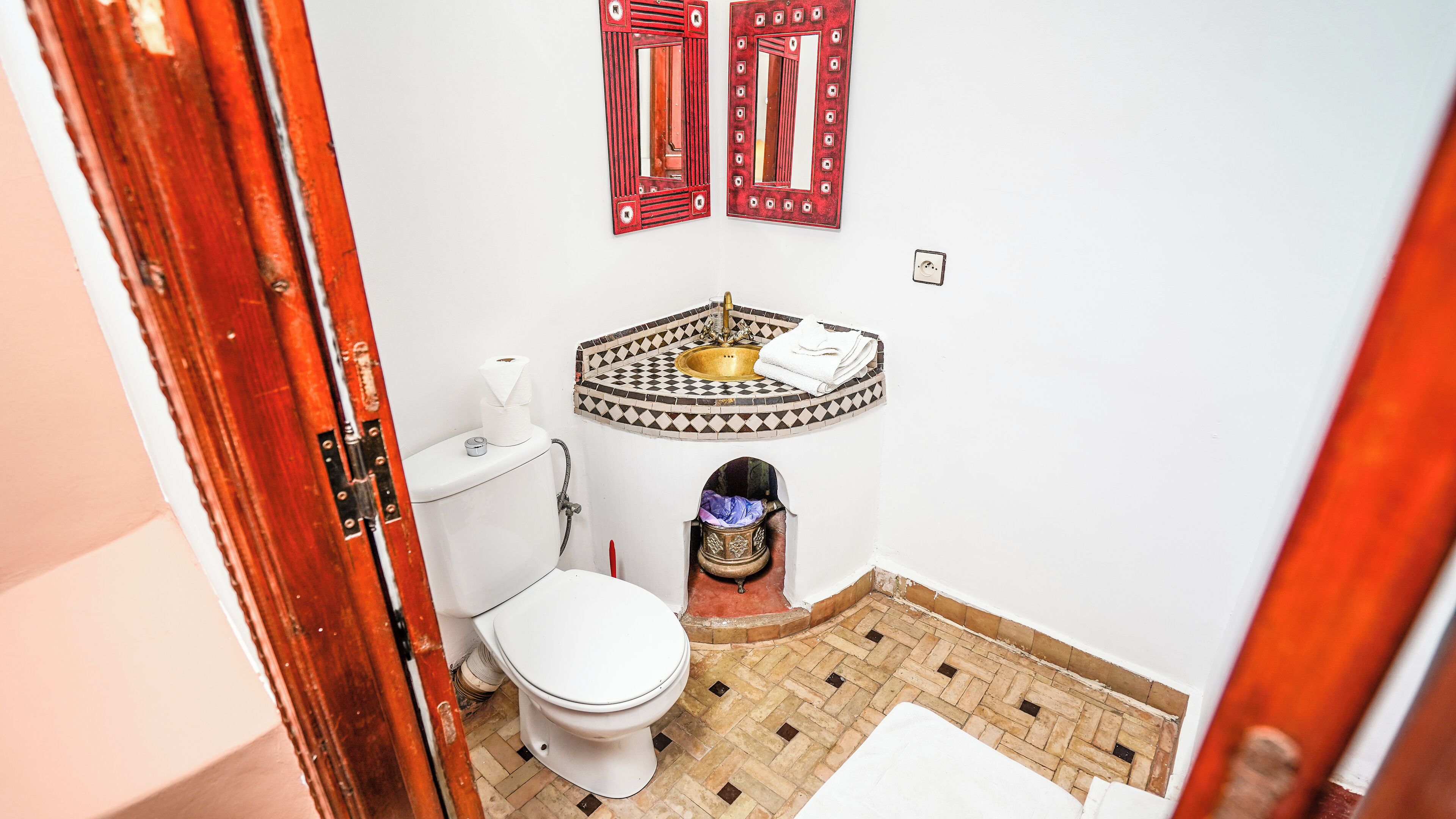 A small bathroom with a toilet, sink, and a decorative mirror.