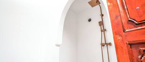 A white arched doorway leading to a shower area with a showerhead and hose.