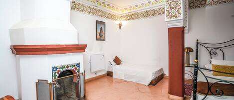 Una habitación con chimenea, una cama, una mesita y una silla.