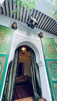 An ornate doorway with intricate patterns and a hanging lantern, leading into a room with a patterned carpet and a sofa.
