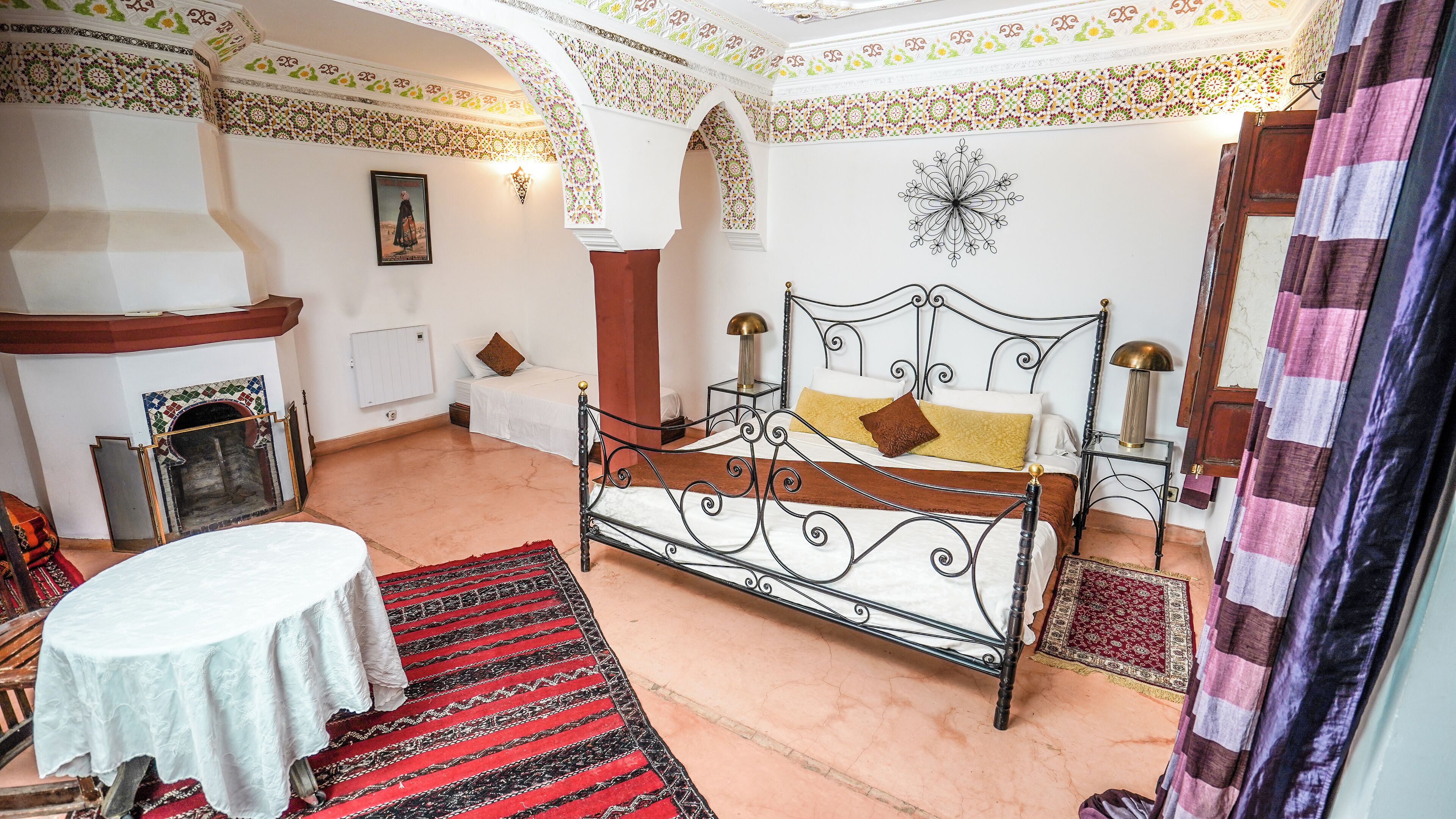 A traditional room with a bed, a table, and a fireplace.