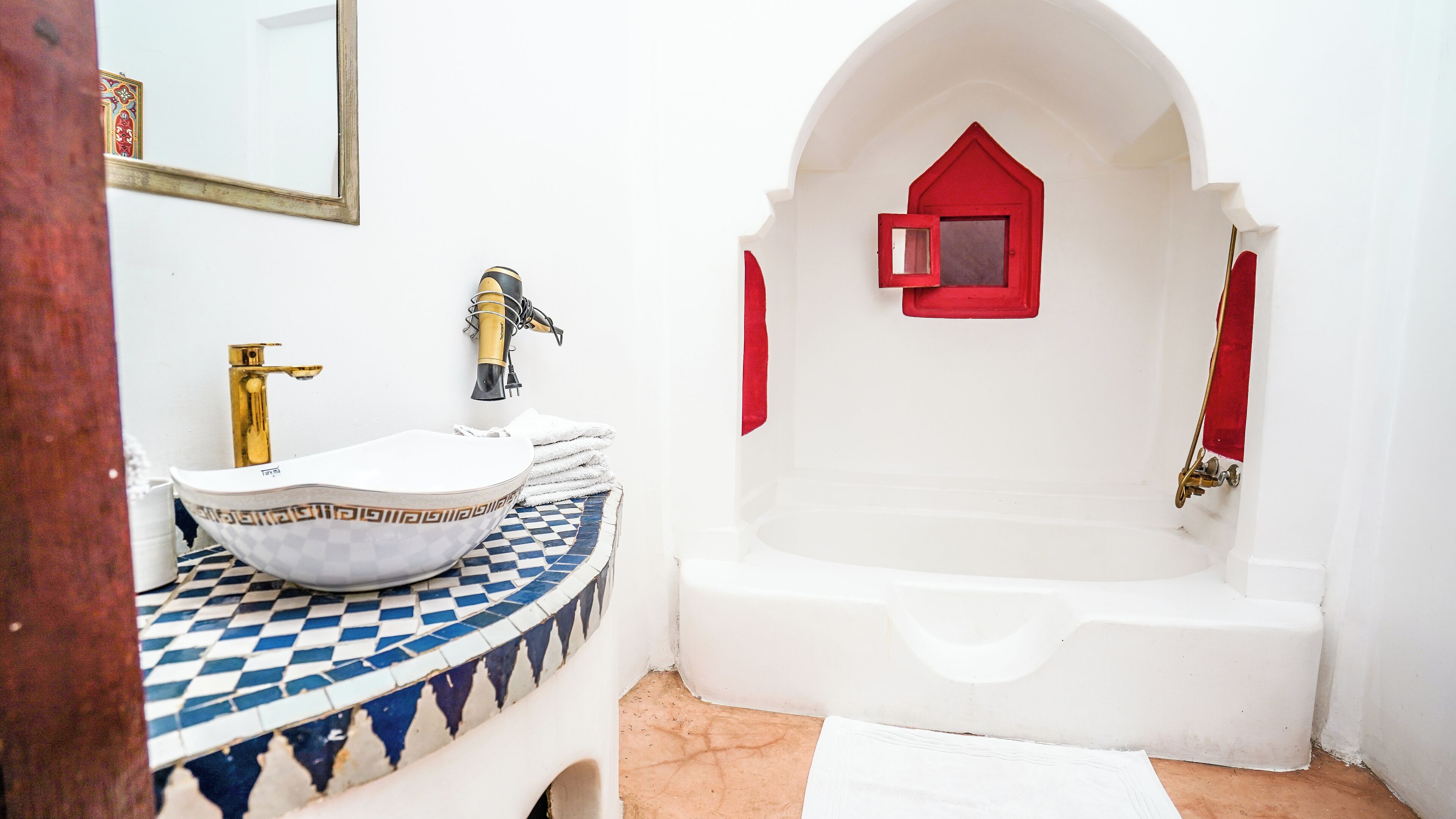 A bathroom with a white sink, a gold faucet, and a checkered tile floor.
