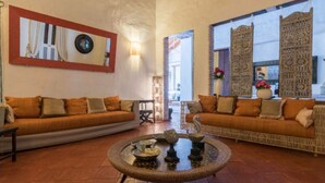 A spacious living area with two sofas facing each other, a coffee table with decorative items, and a wall-mounted clock.