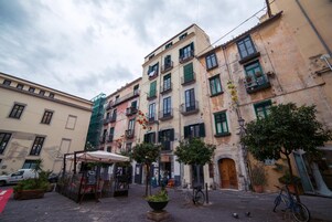 Una calle estrecha con edificios, una bicicleta y una pequeña zona de estar al aire libre.