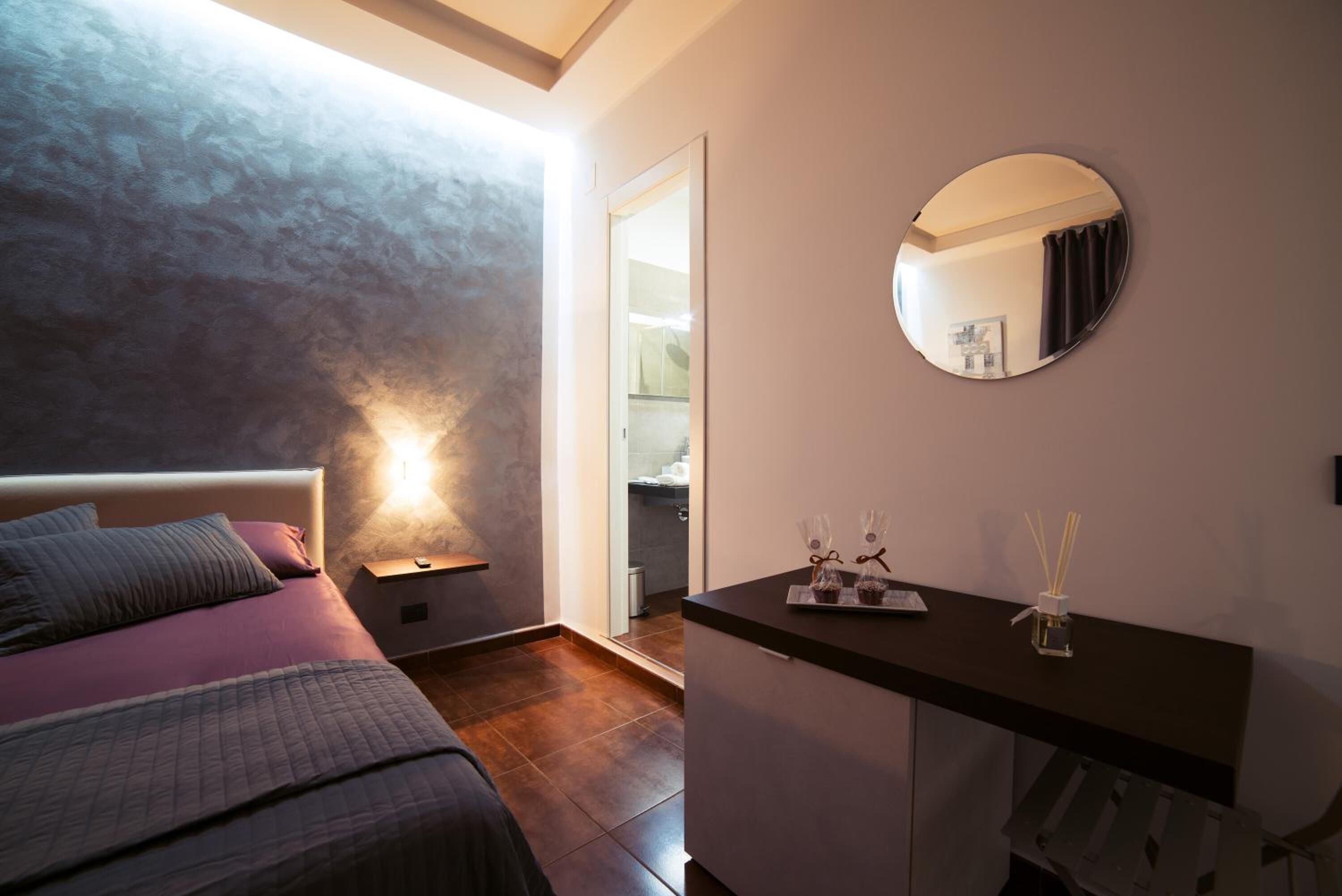 A bedroom with a bed, bedside table, and a mirror on the wall.