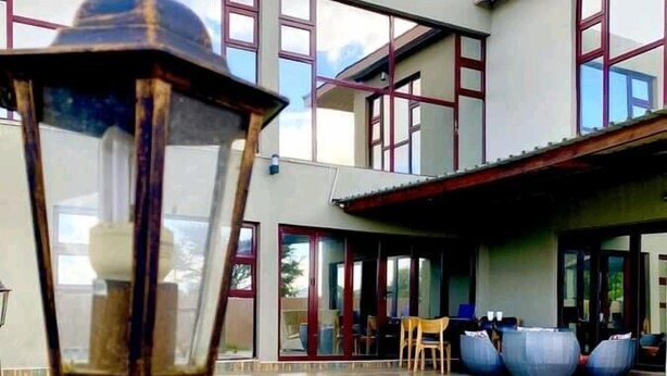 A swimming pool with a modern house in the background. - Kanyi Guest House (Palapye)