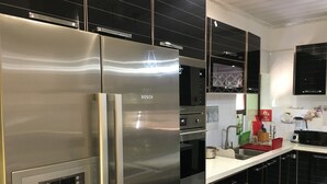 A modern kitchen with a stainless steel Bosch refrigerator, a built-in oven, and a microwave. - Kanyi Guest House (Palapye)