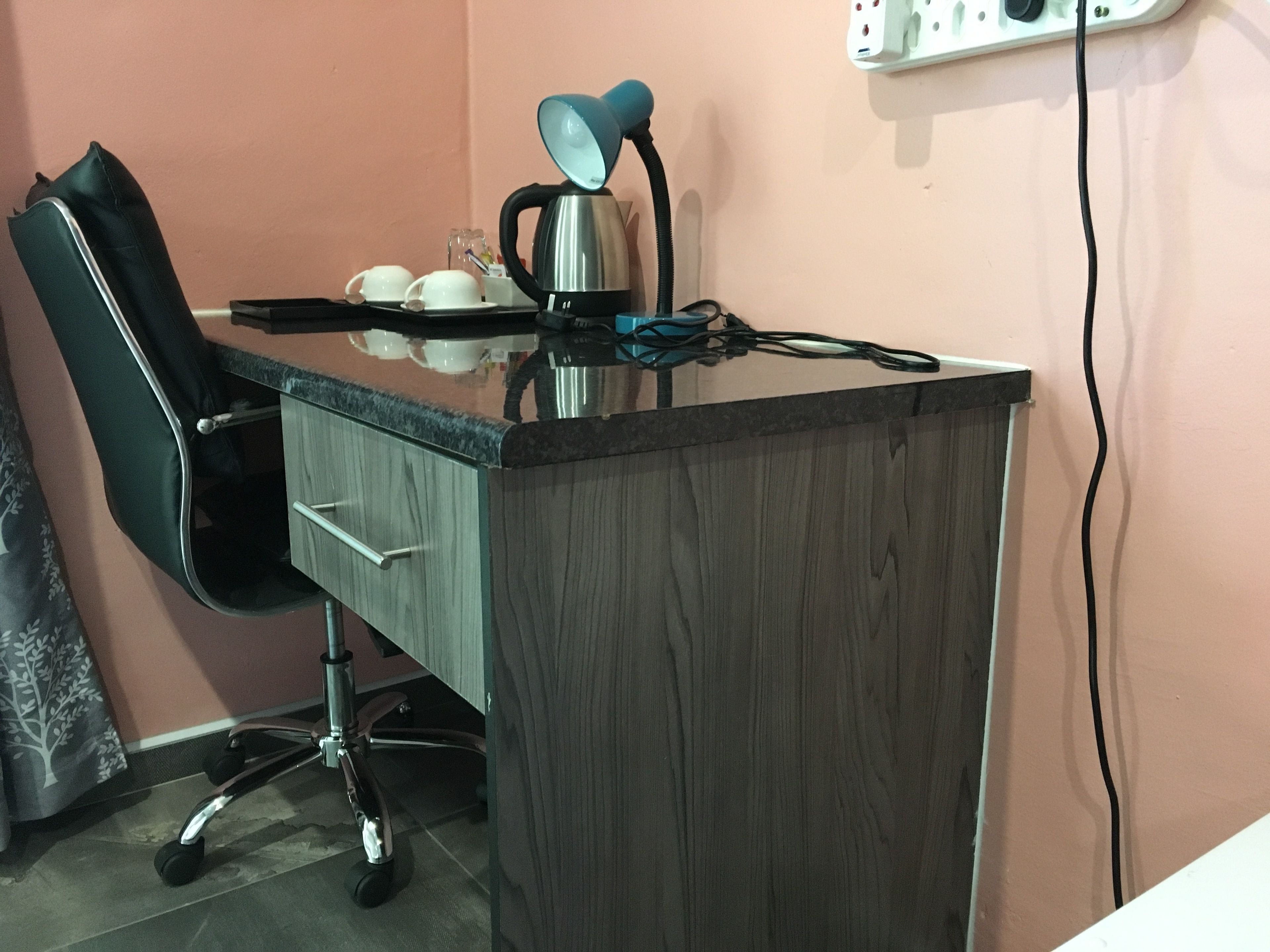 Un escritorio con una computadora portátil, una lámpara y una taza.