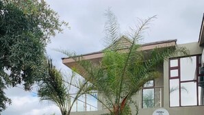 A modern two-story building with a reception area, surrounded by a landscaped garden with various plants and a paved driveway. - Kanyi Guest House (Palapye)