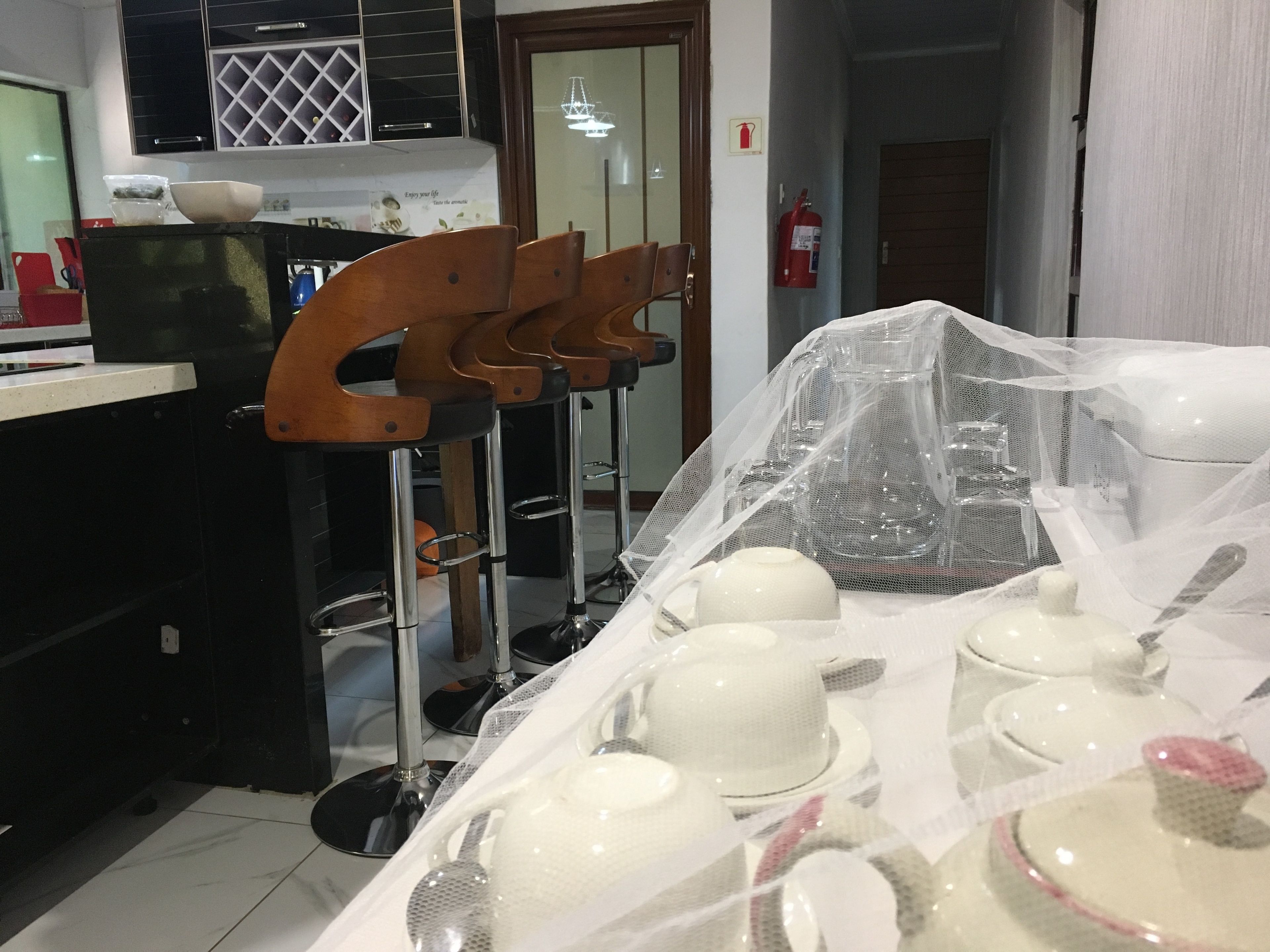 Une cuisine avec une chaise en bois, un extincteur et une table recouverte d’ustensiles de cuisine.