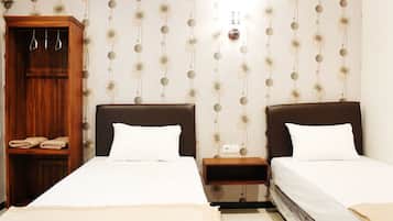 A hotel room with two beds, a wooden wardrobe, and a wall with a circular pattern.