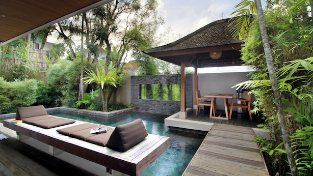 A pool area with lounge chairs and a wooden deck. - Tegal Sari Accomodation (Ubud)
