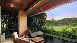 A covered outdoor seating area with wooden furniture and a view of lush greenery. - Tegal Sari Accomodation (Ubud)