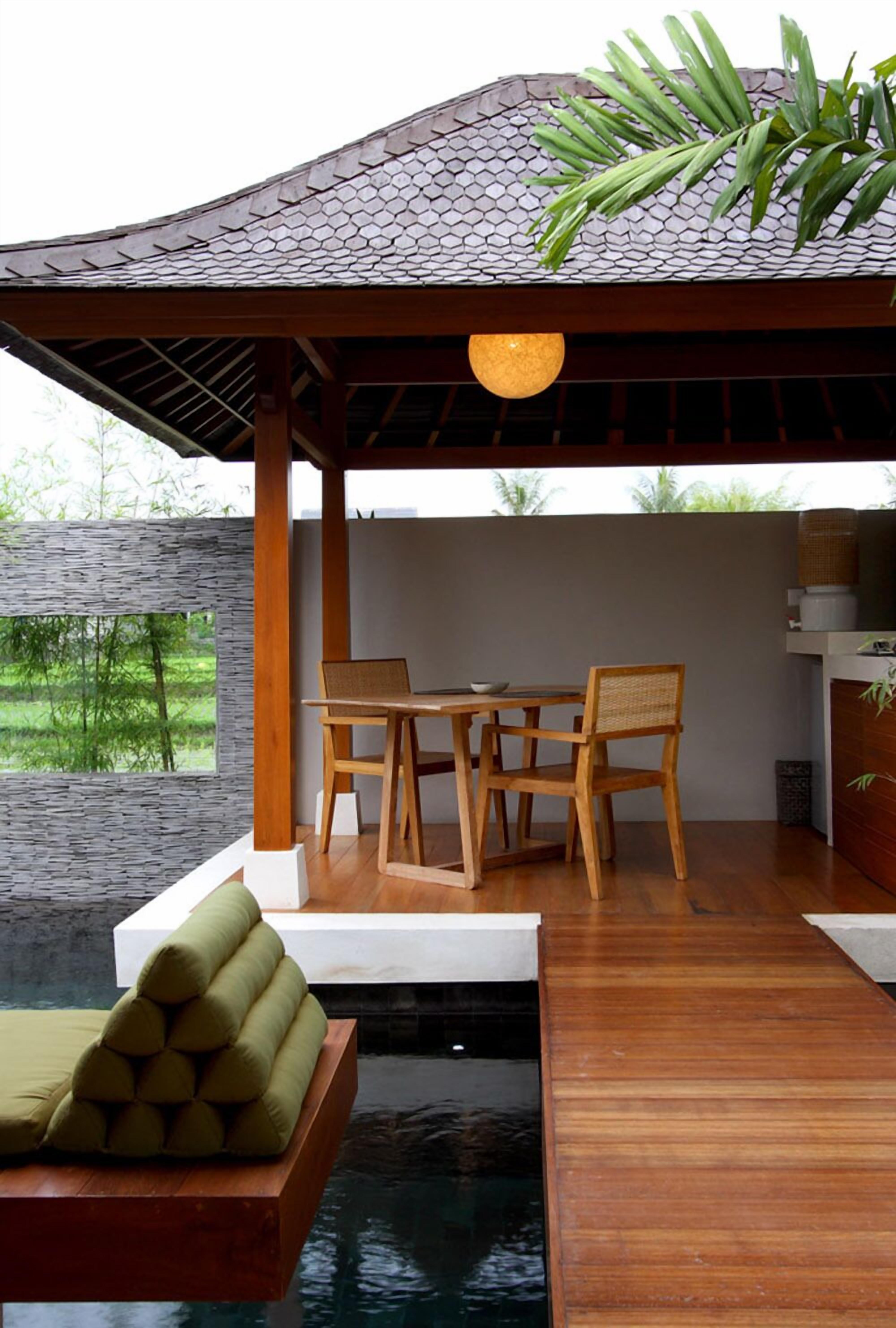 A wooden deck with a table and chairs, a small pool, and a hanging light fixture.