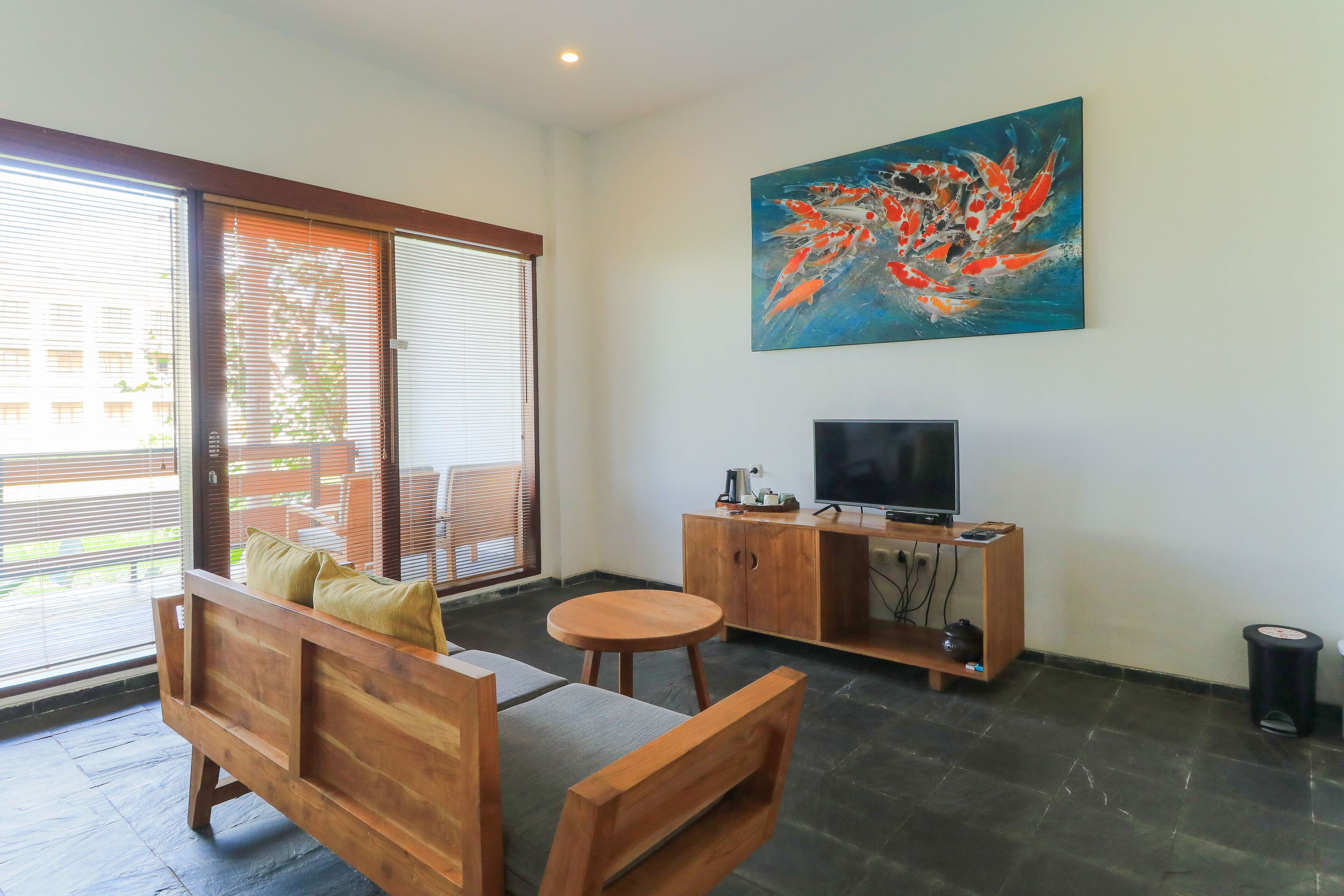 A modern living room with a wooden sofa, a round wooden table, a TV on a wooden cabinet, and a large abstract painting on the wall.