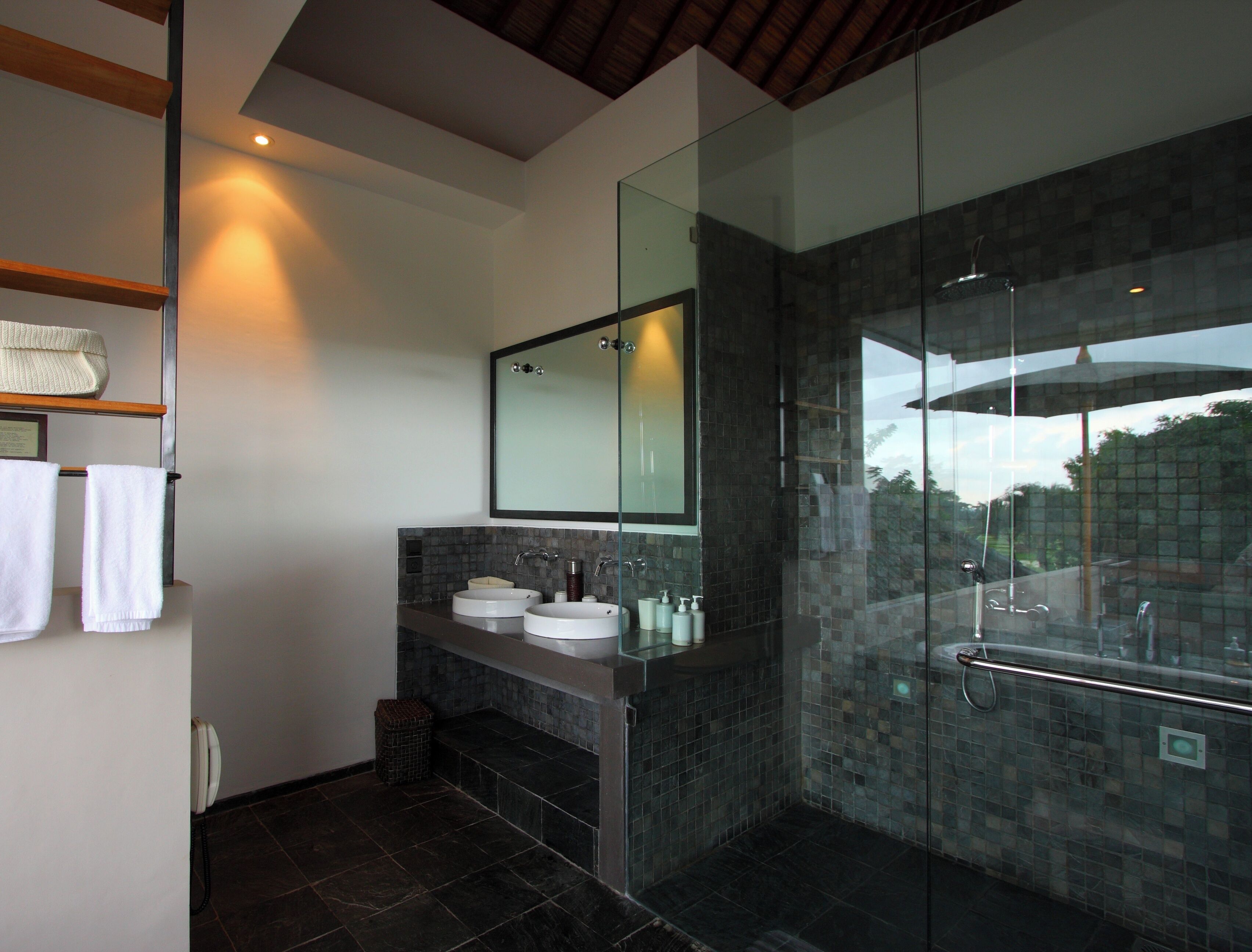 A modern bathroom with two sinks, a large mirror, and a glass-enclosed shower area.