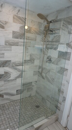 A glass-enclosed shower with a handheld showerhead and a wall-mounted faucet. - GROUND FLOOR STUDIO ~ BEACHSIDE condo with a kitchen, walkout to pool.FN #401 (St Pete Beach)
