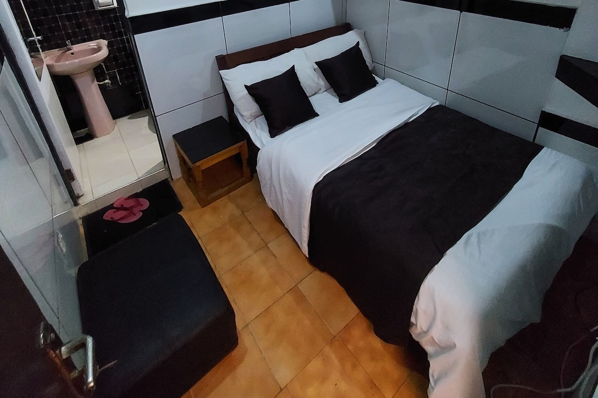 Quarto moderno com cama, mesas de cabeceira, espelho e pia.
