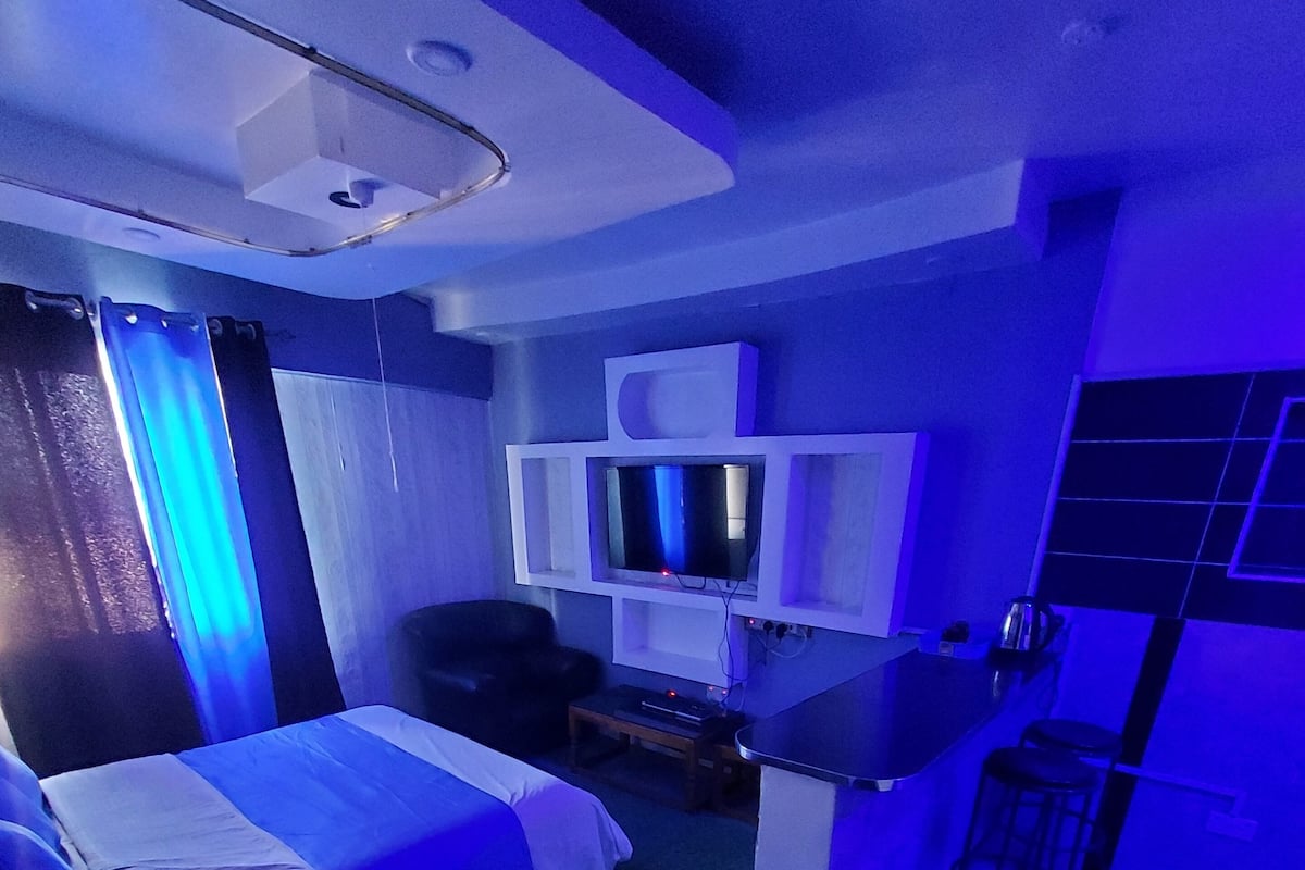 Quarto de hotel moderno com cama, escrivaninha e televisão.