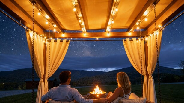 Un couple est assis sur une chaise suspendue, à l’abri d’une tonnelle illuminée de guirlandes lumineuses, et contemple un ciel nocturne étoilé ainsi qu’un paysage montagneux.