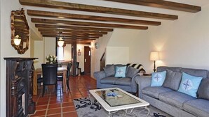 A living room with a sofa, coffee table, and fireplace. There is a dining area with a table and chairs in the background. - Monaco Resort - Home to Compass Cottage (Monaco)