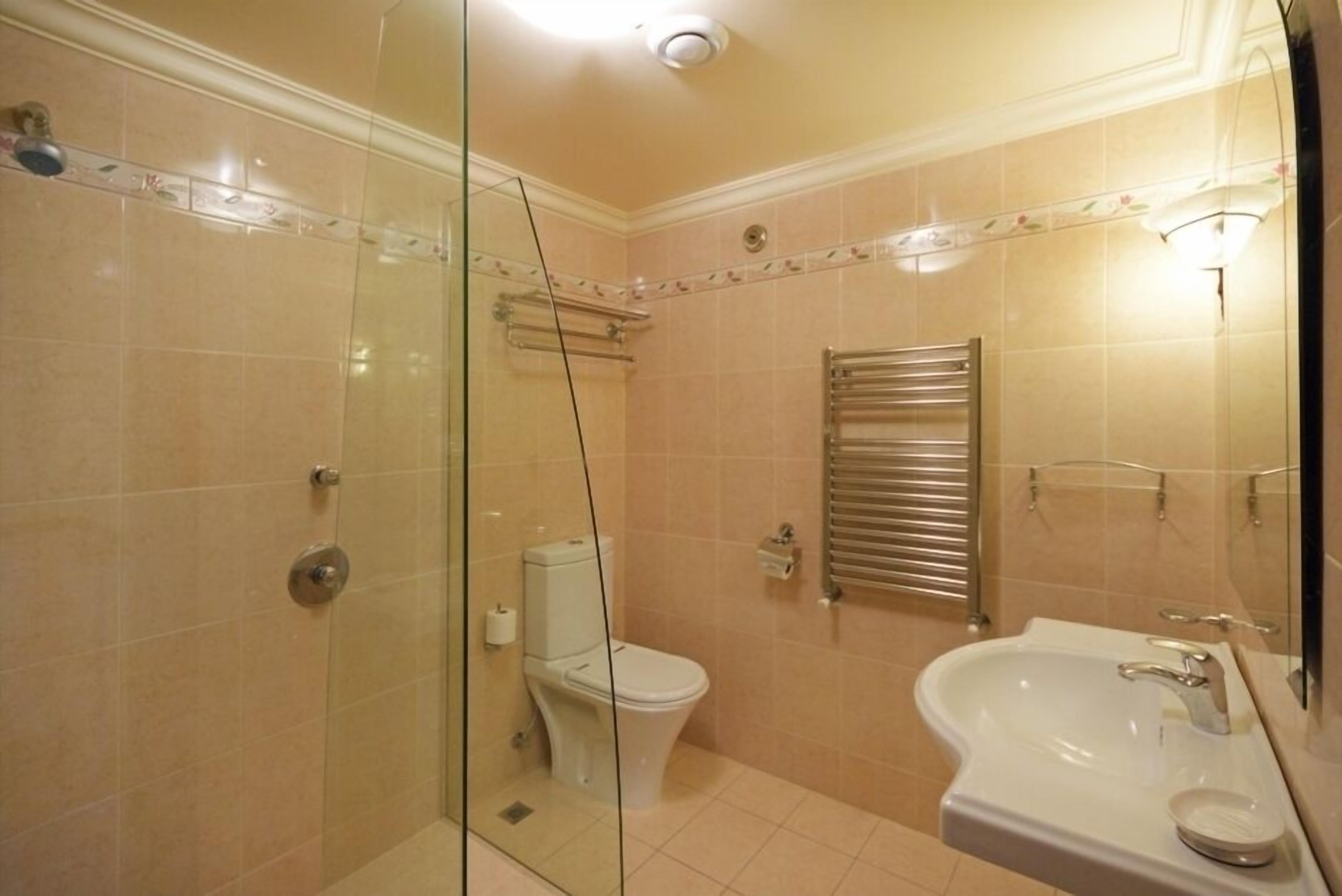 Een badkamer met een douchecabine van glas, een toilet en een wastafel met spiegel.