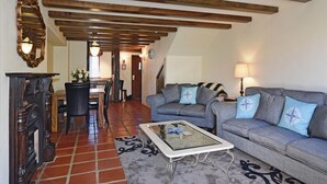 A living room with a sofa, coffee table, and fireplace. There is a dining area with a table and chairs in the background. - Monaco Resort - Home to Compass Cottage (Monaco)