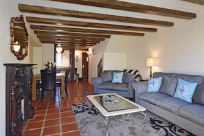 A living room with a sofa, coffee table, and fireplace. There is a dining area with a table and chairs in the background. - Monaco Resort - Home to Compass Cottage (Monaco)