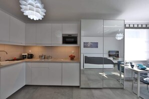 A modern kitchen with white cabinets, a microwave, and a coffee maker.