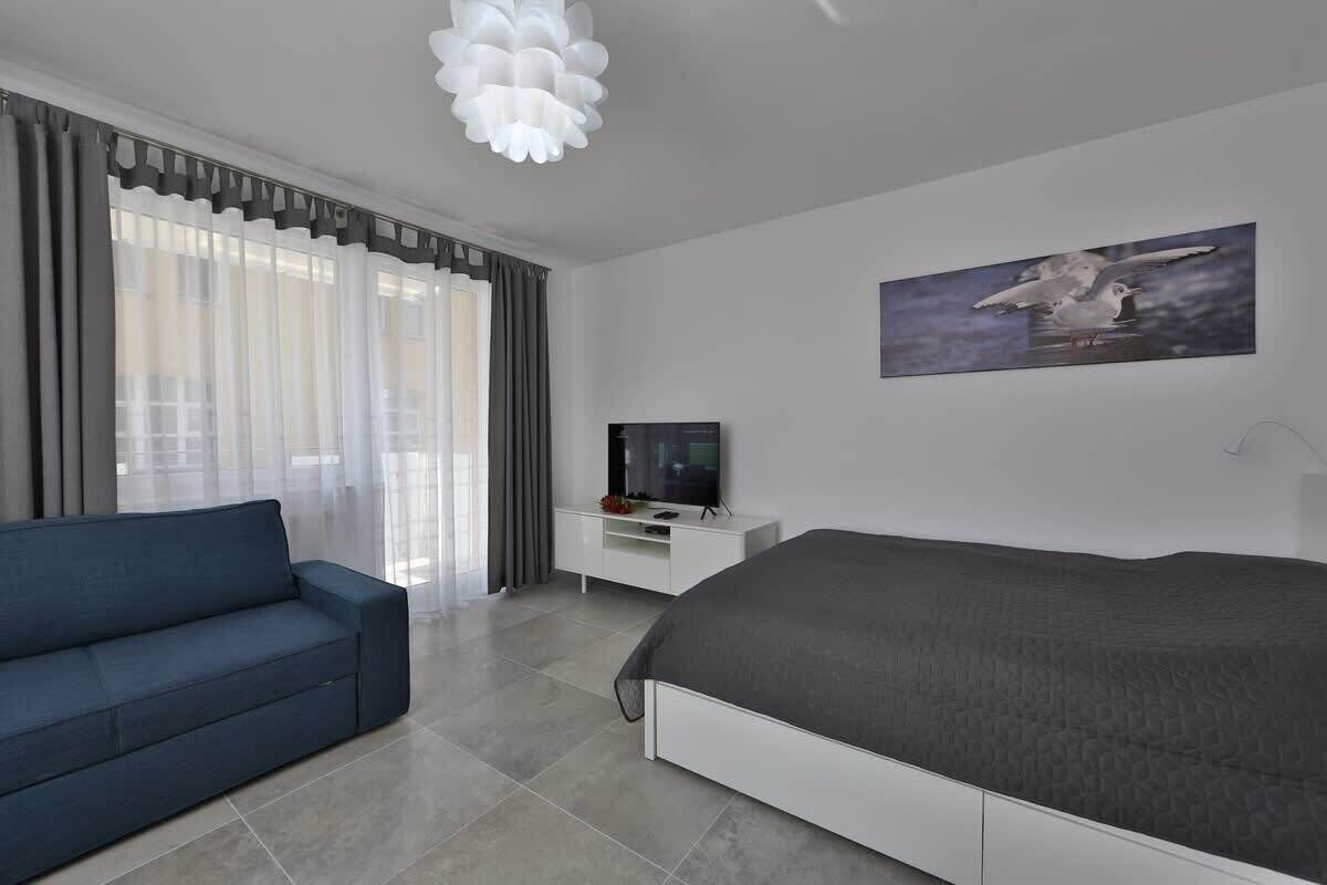 Habitación de hotel moderna con una cama, un sofá, un televisor y un cuadro en la pared.