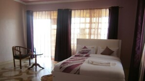 A hotel room with a bed, a chair, and a small table. - Elgon Village Guest House (Eldoret)