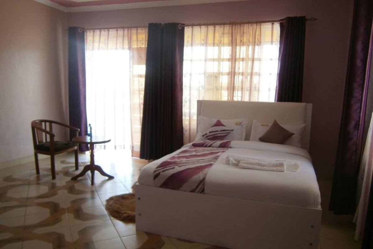 Quarto de hotel com uma cama, uma cadeira e uma pequena mesa.