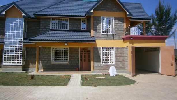 A two-story house with a stone facade, a tiled roof, and a front porch. - Elgon Village Guest House (Eldoret)