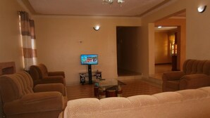A living room with sofas, a coffee table, and a television. - Elgon Village Guest House (Eldoret)