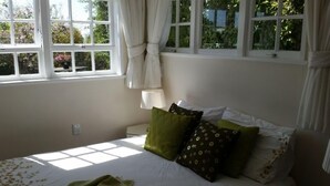 Ein Schlafzimmer mit Bett, Kissen und einem Fenster mit Vorhängen.