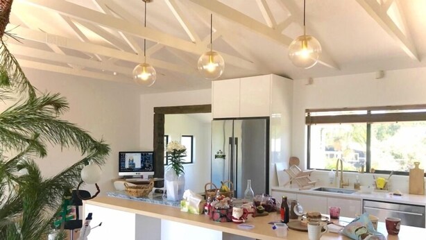 A modern kitchen with a central island, bar stools, and a large window providing natural light.