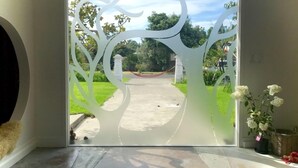 A glass door with a tree design, leading to a pathway and greenery.