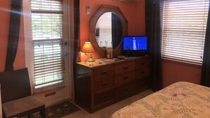 Un dormitorio con cama, cómoda, televisión y aire acondicionado.
