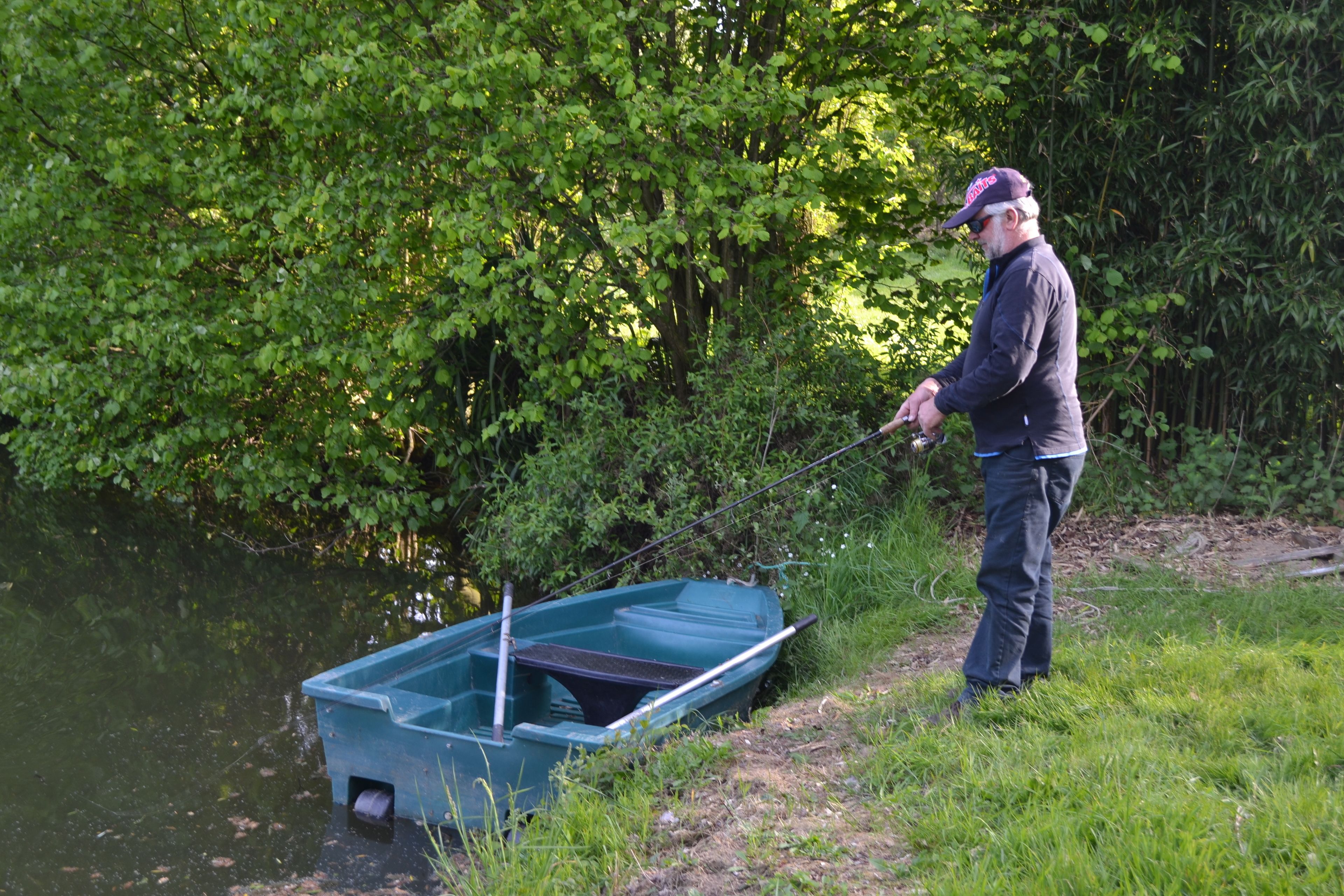 Ein Mann fischt an einem ruhigen Fluss mit einem kleinen Boot.