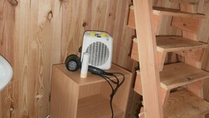 A wooden staircase in a room with a white fan on a wooden shelf.